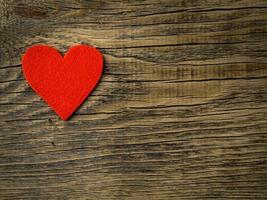 corazón rojo brillante único sobre fondo de madera vieja de textura vintage oscura, símbolo del día de san valentín, espacio de copia para texto, vista superior. foto