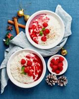 Rice pudding. Christmas food. French milk rice dessert with raspberries. Dark background, vertical