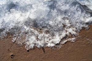 Ice on beach. Border of winter and summer. Ice and sand. Cold and warm. Contrast transition photo