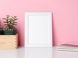 Blank white frame and plant cactus on a white table against the pink wall with copy space. Mockup with copy space. photo