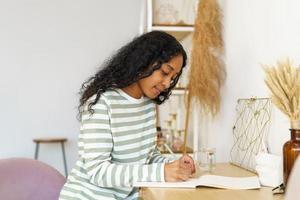 diario femenino afroamericano en cuaderno. haciendo notas en el diario. concepto de atención plena foto