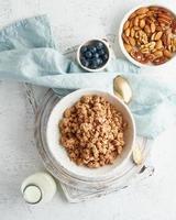 Dry granola in bowl. Breakfast, healthy diet food with milk in bottle, oat flakes photo