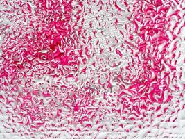 Abstract pink and white background with large and small convex drops of water on glass, condensation on window. Macro, close up. photo