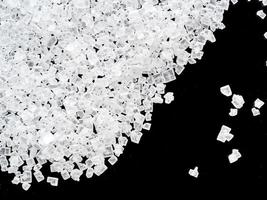 white crystals of sugar on black background, close-up, top view. photo