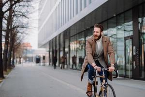 Young hipster businessman going to work on bike. Eco friendly transport concept photo