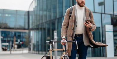 parte media del hombre de negocios hipster usando la navegación de aplicaciones móviles. foto de cubierta. ubicación del centro de negocios. yendo a trabajar