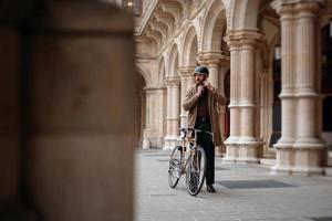 joven empresario se está poniendo casco antes de andar en bicicleta. viajar al trabajo. seguridad y transporte ecologico foto