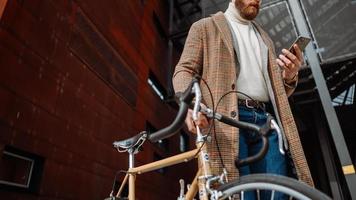 detalle de la sección media de la mano con el teléfono. hombre de negocios con teléfono móvil. en el camino al trabajo con bicicleta foto