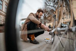Man checking wheels on bike. Repairing bicycle at street. photo