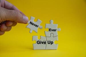 Motivational text on jigsaw puzzle with hand holding a missing jigsaw - Never ever give up. photo