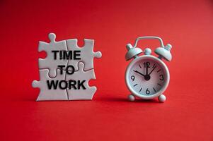 Time to work text on jigsaw puzzle with alarm clock pointing at 10 o'clock. Working and Business concept photo