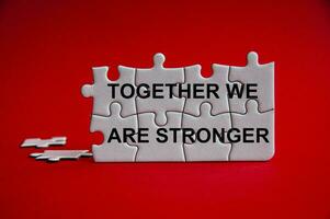 Together we are stronger text on jigsaw puzzle with red background. photo