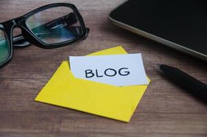 Blog text on small piece of paper in an envelope with office concept background. Online marketing concept photo