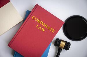 vista superior del libro de derecho corporativo con mazo sobre fondo blanco. foto