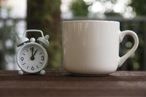 Alarm clock pointing at 1 o'clock with coffee cup on a bench. Copy space concept photo