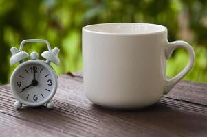 despertador apuntando a las 8 en punto con una taza de café en un banco. concepto de espacio de copia