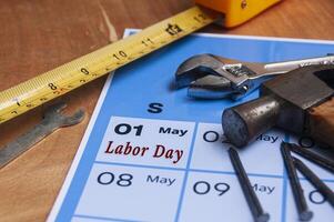 Side view of Labor Day text on calendar with working tools background. Labor day concept. photo