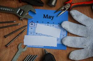 Top view of calendar and empty torn paper with working tools background. Labor day concept photo