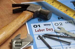 Side view of Labor Day text on torn paper with calendar and working tools background. Labor day concept. photo