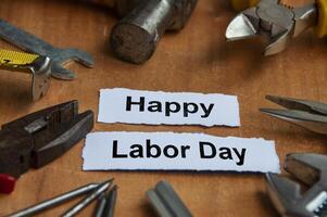 Happy labor day text on torn papers with working tools background. Labor day celebration concept. photo