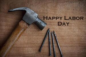 Top view of text on wooden desk - Happy Labor Day with hammer and nails background. photo
