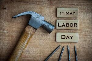 Top view of text on wooden blocks - 1st May. Labor day with hammer and nails background. photo