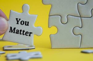 Motivational text on jigsaw puzzle with yellow background - You matter.