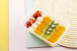 pudín de gelatina fría con lichi fresco y frutas de cóctel mixtas en la parte superior en un menú de postres de caja bento transparente de plástico foto