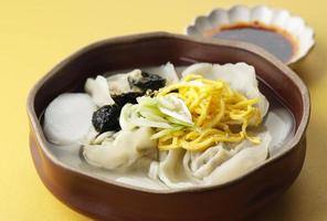 comida tradicional coreana sopa de pastel de arroz en rodajas, tteok y sopa de bola de masa hervida foto