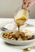 Pour Brown Mushroom Sauce to Swedish Meatball with Vegetable, Lingeonberry Sauce, and Mashed Potato
