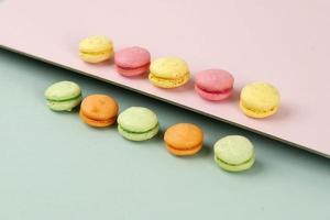 Creative layout made of colorful macaroons on the mint and pink background photo