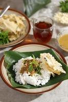 Sego Pecel Tumpang, Traditional Breakfast with Rice Nasi Topping with Tempeh and Boiled Vegetable, Served with Peyek Crackers. photo