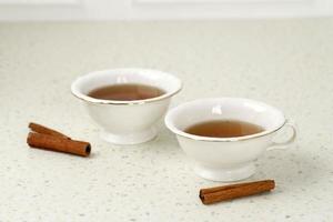 Glass cup of tea with cinnamon sticks. White background. Isolated. photo