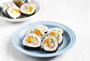 rollo coreano gimbap kimbob o kimbap hecho de bap de arroz blanco al vapor y varios otros ingredientes, como kyuri, zanahoria, salchicha, palito de cangrejo o kimchi y envuelto con algas marinas foto