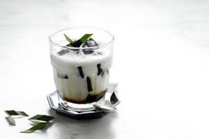 es cincau hitam o jalea de hierba negra cincau hitam, postre indonesio elaborado a base de hoja de cincau con leche de coco y azúcar de palma. foto