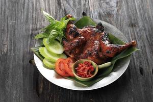 Ayam Bakar Bakakak or Whole Roasted Chicken with Sweet Soy Sauce, Served with Sliced Cucumber, Tomato, and Basil Leaf. photo