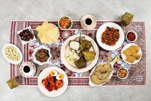 Ketupat Lebaran, Indonesian Ied Menu Dish, Opor Ayam, Sambal Goreng Ati Kentang, Balado Telur, Dates Fruit, Sambal, Lapis Legit, and Tea. photo