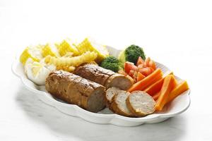 Meatloaf with Spicy Glaze Sliced on a Plate, Ground Beef and Pork Dish, Served with Steamed Vegetable, on White Table photo