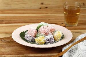 colorido ongol-ongol o sentiling, pastel de mandioca al vapor con coco rallado, servido en plato de cerámica foto