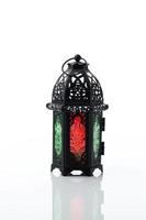 Ornamental Arabic lantern with burning candle glowing on white background.