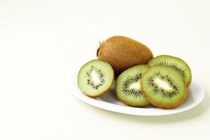kiwi verde maduro en rodajas en un plato blanco foto
