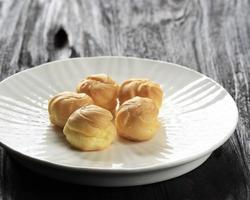 Homemade small cakes profiterole choux pastry with custard photo