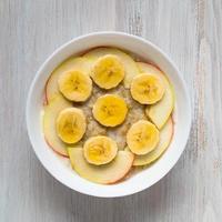 Healthy Breakfast in the morning - oatmeal with fruit and honey, slices of apples and bananas, caramel syrup. photo