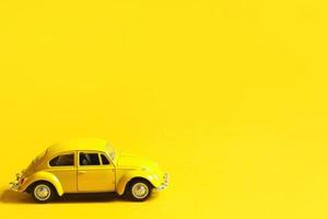 Yellow toy car on a colored background. Copy space. Children's toy, taxi, retro car, summer, travel. photo