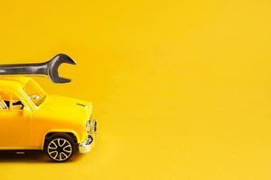 Auto repair and repair of equipment and cars, urgent departure of the master to eliminate breakage, plumbing work, construction. Repair service car with adjustable universal key on yellow background. photo