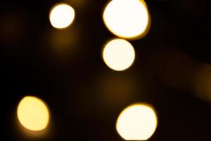 guirnalda de luces amarillas y doradas en un desenfoque sobre un fondo negro. bokeh de círculos voladores en el desenfoque. ambiente festivo de navidad y año nuevo. celebrar fondo foto