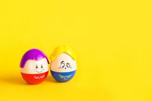 dos huevos divertidos niño y niña con caras sobre un fondo amarillo - pascua, primavera. juguetes para niños: un símbolo de una pareja de hombres y mujeres, amor, familia. copie el espacio foto