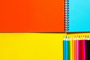 Rainbow palette of colored pencils with a spiral notebook on a yellow background,mock up, flat lay. Back to school, student recruitment, artist, drawing lessons. Copy space. Stationery for creativity photo