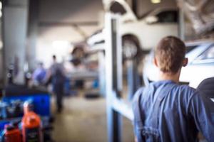 Car repair service in defocus, industrial background. Cars on lifts, transport service area, the mechanic repairs the car. Copy space photo