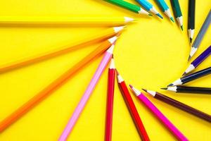 Set of colorful pencils on a yellow background is laid out in a circle in the shape of the sun. Copyspace, frame. Back to school, artist, drawing lessons. Stationery for creativity, draw photo